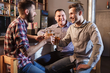 Happy friends drinking beer at counter in pub