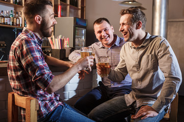 Happy friends drinking beer at counter in pub