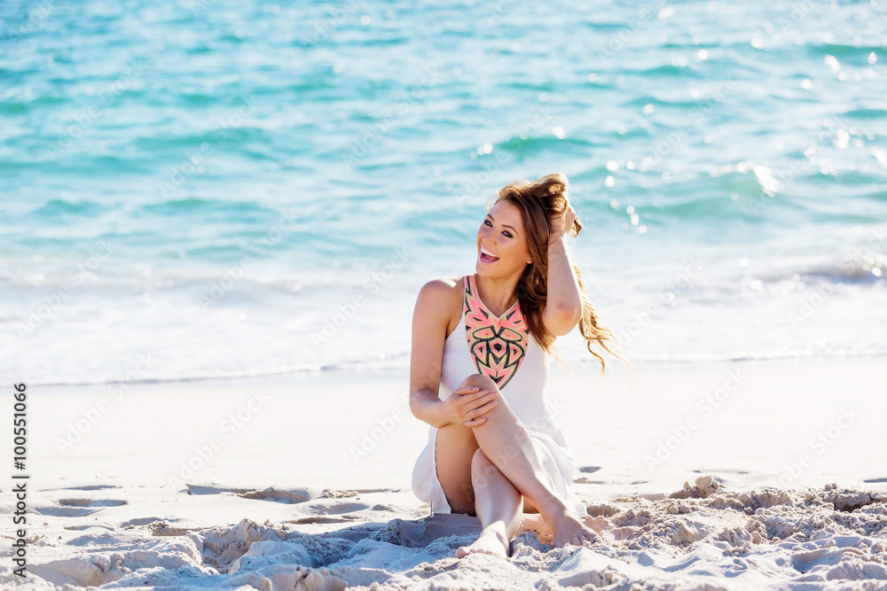 Poster young woman sitting on the beach