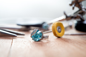 Desktop jeweler. silver ring with blue stone on the table with jewelry tools