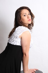 Beautiful  teenager in a black and white topped dress against a light colored background.