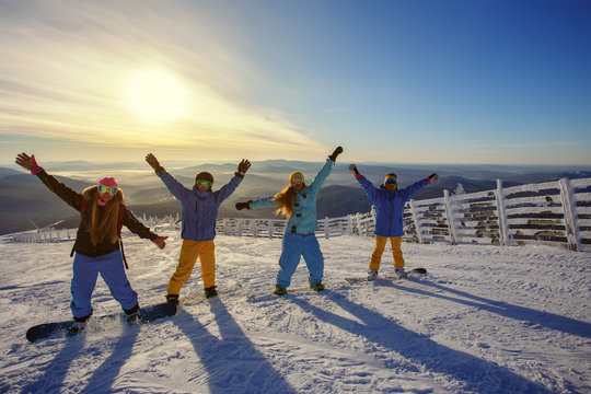 Group of friends snowboarders having fun on the top of mountain