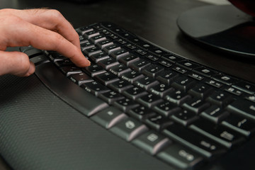 Man typing on a keyboard with letters in Hebrew and English - Wireless keyboard