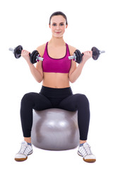 Fototapeta na wymiar young woman in sports wear sitting on fitness ball with dumbbell