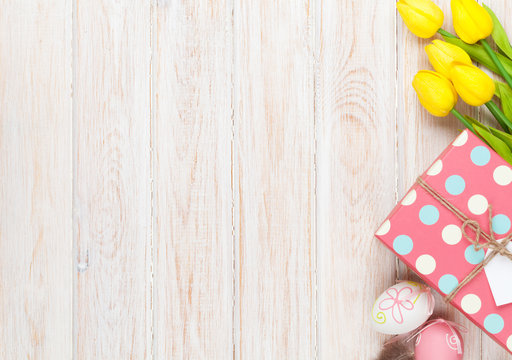 Easter background with colorful eggs and yellow tulips