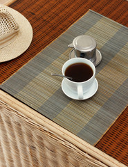 Morning coffee served in vietnam coffee filter on rattan table, natural light photo