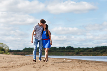 A young couple walks along the beach.