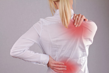 Woman with neck / back pain. Business woman rubbing her painful back close up. Pain relief concept
