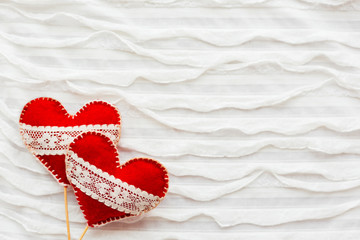 Fototapeta premium White fabric background with ruche.Two felt hearts with laces, symbol of love. Good for Valentine's Day cards. Place for text.