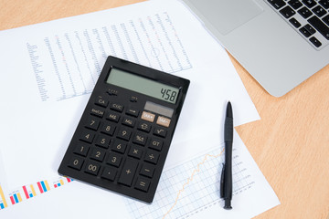 Laptop with business charts and calculator on the desk