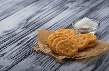 Salty cracker and salt on wooden background