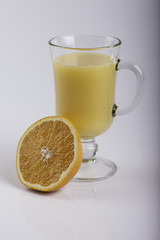 glass of juice and a sliced orange on white