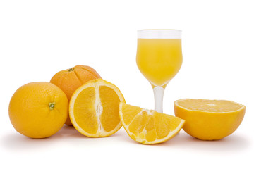 Pieces of orange, ripe oranges in background and glass of orange juice isolated on white. Clipping path incl.