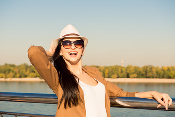 stylish happy young woman enjoying the sun by the river