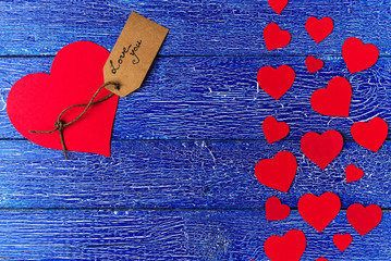Red heart paper cut on blue wooden background.