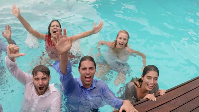 Happy friends with clothes in the pool
