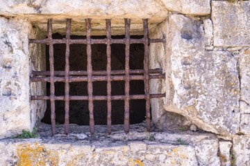 old window with a rusty lattice on stone wall