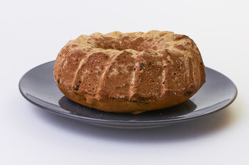 cake with raisins on dark ceramic plate separated over white background