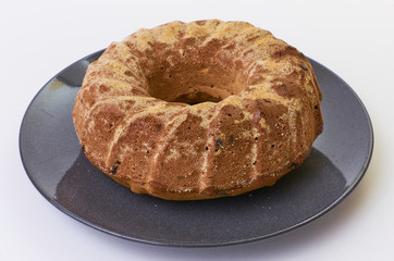 cake with raisins on dark ceramic plate separated over white background