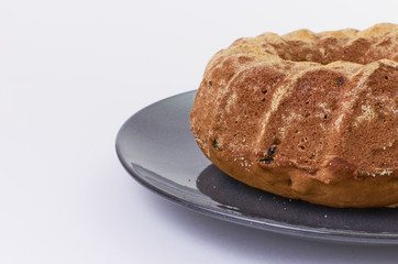 cake with raisins on dark ceramic plate separated over white background