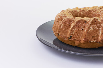 cake with raisins on dark ceramic plate separated over white background