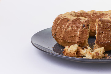 cake with raisins on dark ceramic plate separated over white background