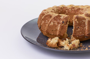 cake with raisins on dark ceramic plate separated over white background