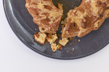 cake with raisins on dark ceramic plate separated over white background