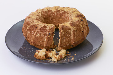 cake with raisins on dark ceramic plate separated over white background