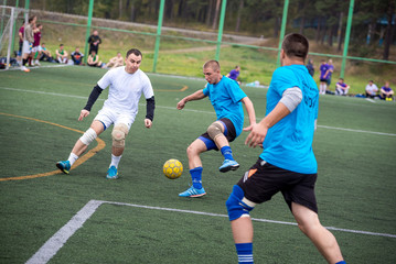 Men playing street soccer. Emotional moment. Three 3 players running after the ball. On the grass...