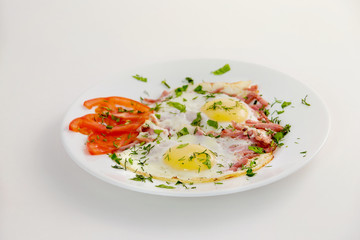 Closeup image of plate of fried eggs with fresh tomato and bacon