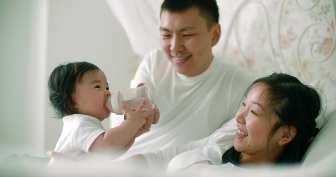 young Asian family with a 6 month child on the bed