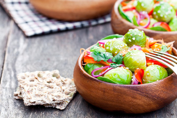 Portion  of Brussel Sprouts with carrot and onions on wooden tab