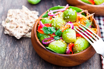 Portion  of Brussel Sprouts with carrot and onions on wooden tab