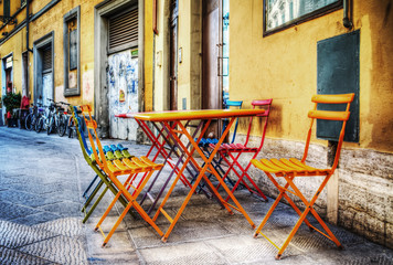 Fototapeta na wymiar colorful tables and chairs on the sidewalk in Florence