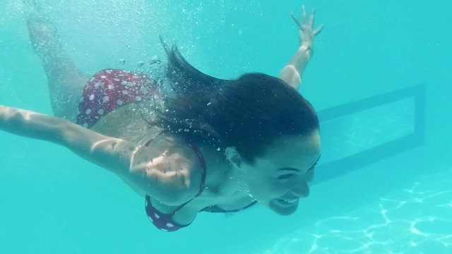 Smiling woman swimming underwater