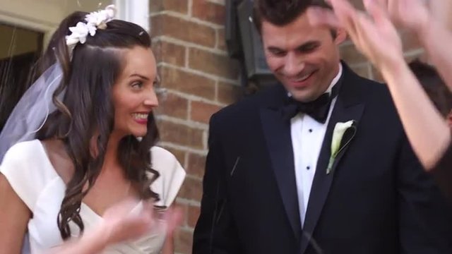 Bride and groom under thrown rice at wedding, traditional, slow motion.