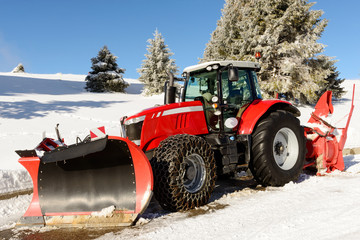 large red tractor with snow plow  during a winter