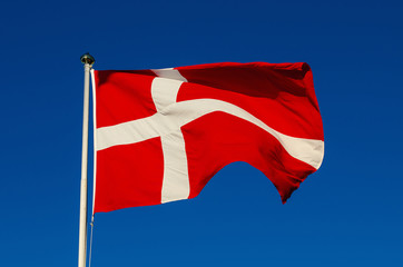 Flag of Denmark against the blue sky, national patriotic background