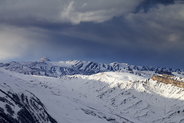 Winter mountains at evening and storm clouds