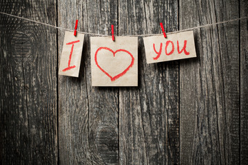 Handwritten words I love you and hearts on wooden background.