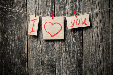 Handwritten words I love you and hearts on wooden background.