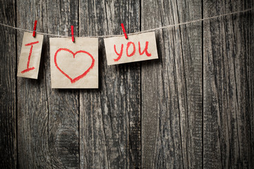 Handwritten words I love you and hearts on wooden background.