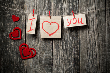 Handwritten words I love you and hearts on wooden background.