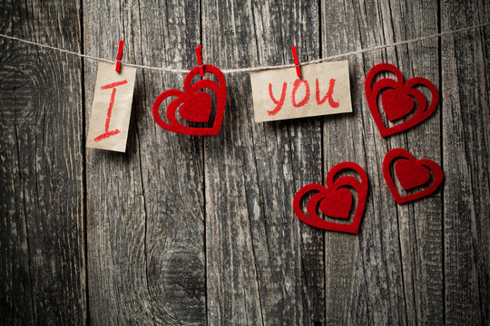 Handwritten words I love you and hearts on wooden background.