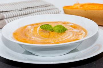 Crema de calabaza en un plato y varias semillas de calabaza