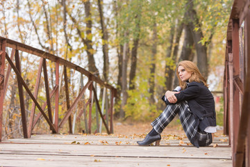 Sad girl sitting on a bridge in the forest