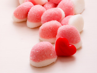 Pink jellies or marshmallows with sugar on table