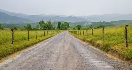 The Journey. Dirt road leads to a Smoky Mountain horizon shrouded in fog. Cades Cove. Great Smoky Mountain National Park. Gatlinburg, Tennessee.
