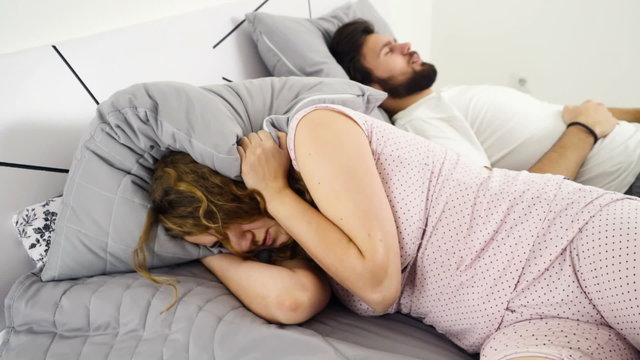 woman hiding her head under the pillow while sleeping with a man slow motion